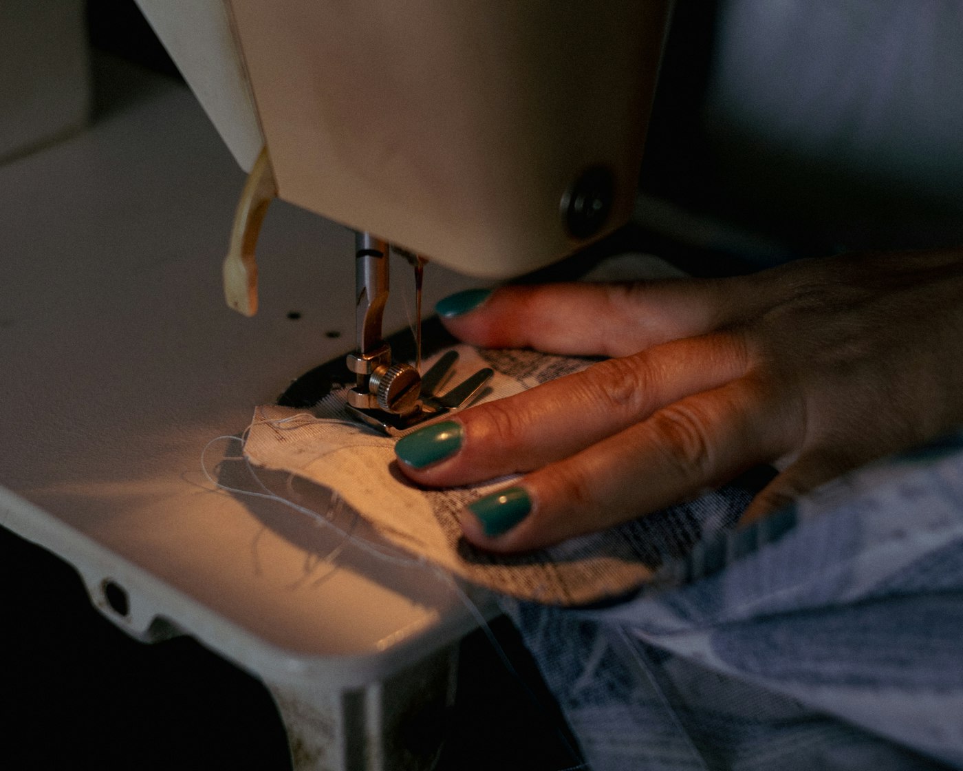 Mains d'une opératrice guidant le tissu sur machine à coudre